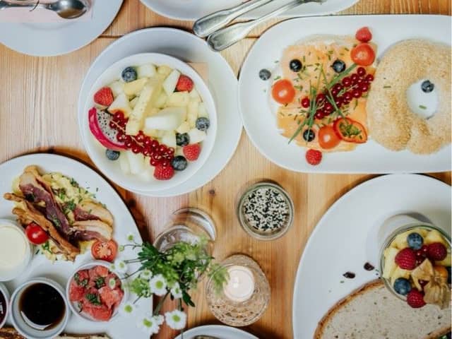 Gedeckter Brunchtisch von oben mit Bowls, Obst und Kaffee