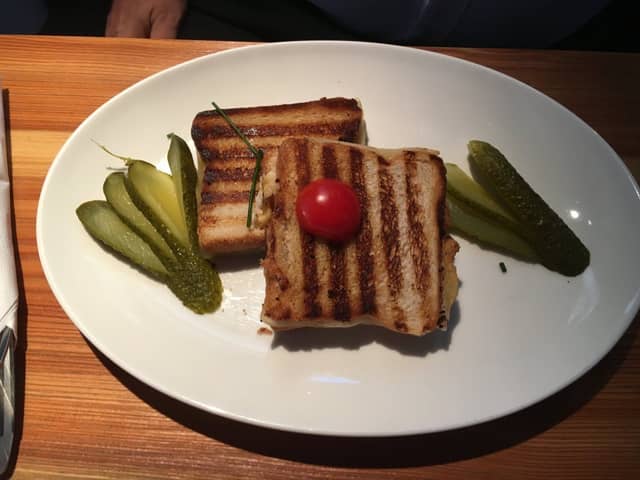 Zwei gegrillte, gebutterte Toastscheiben mit Essiggurken auf weißem Teller
